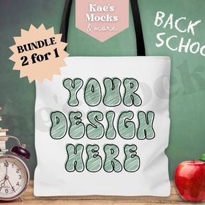 May include: White tote bag mockup with the text "YOUR DESIGN HERE" written in green and black on the front. The bag is sitting on a wooden surface in front of a green chalkboard with the text "BACK TO SCHOOL" written in white chalk. There is a red apple and an alarm clock on the surface.