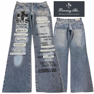 May include: Light blue denim jeans featuring a wide-leg silhouette, distressed wash, and numerous black printed text graphics and patches. The front displays a large cross, the text BGS, SOMEWHAT, and BERNINGS-SHO, while the back shows two pockets.