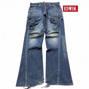 May include: Blue denim jeans with large cargo pockets on the thighs. The jeans have a faded wash and a flared leg design. The brand name "EDWIN" is displayed in a red rectangle.