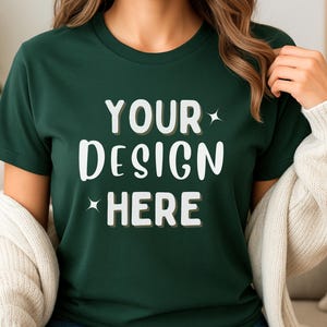 May include: A dark green t-shirt with the text "YOUR DESIGN HERE" in white lettering.