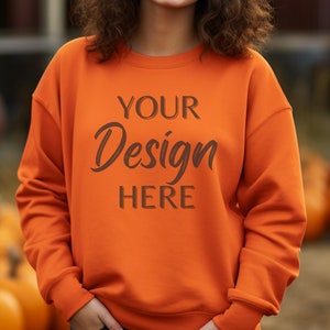 Könnte beinhalten: Ein leuchtend orangefarbener Pullover mit dem Aufdruck "YOUR Design HERE" auf der Vorderseite.