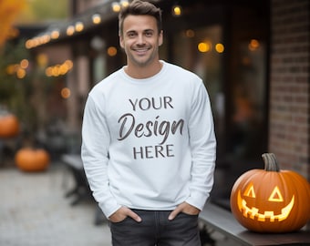 以下が含まれることがあります： 白いスウェットシャツに「YOUR Design HERE」という文字がプリントされています。スウェットシャツは、レンガ造りの建物の前に立っている人が着用しています。