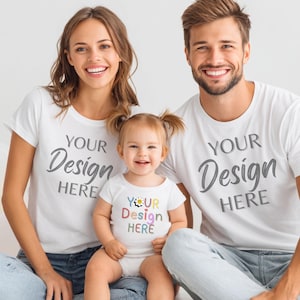 May include: Three people wearing white t-shirts and jeans. The adults' shirts say "YOUR Design HERE" in gray script. The child's onesie has a colorful floral design and says "YOUR Design HERE".