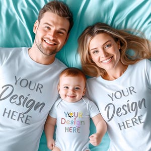 Può includere: Una famiglia di tre persone indossa magliette bianche abbinate e un body per neonati. Le magliette e il body hanno la scritta "YOUR Design HERE" in un carattere grigio. Il body del bambino ha un colorato disegno floreale con la scritta "YOUR Design HERE".