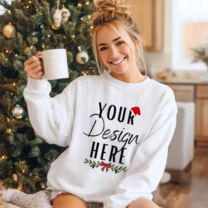 Könnte beinhalten: Weißes Sweatshirt mit Rundhalsausschnitt und dem Text "YOUR Design HERE" in schwarzer Schrift und Blockbuchstaben. Ein kleiner roter Weihnachtsmannhut befindet sich über dem Wort "Design".