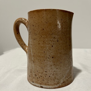 May include: A brown ceramic pitcher with a speckled glaze. The pitcher has a rounded body and a handle.