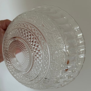 May include: A clear glass bowl with a decorative, raised pattern. The bowl has a scalloped edge and a diamond-shaped pattern in the center.