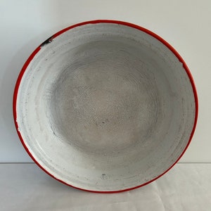 Peut inclure: Bol en émail blanc avec un bord rouge. Le bol a un aspect usé et vintage.