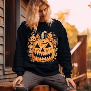 Halloween Clip Art with Skull, Pumpkin, and Hearts arranged in a heart shape on a Fall background mockup of a black sweater design