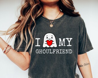 May include: Dark grey t-shirt featuring the text "I MY GHOULFRIEND" and a cartoon ghost with a red heart. This casual tee is ideal for Halloween or any spooky occasion, offering a relaxed fit.