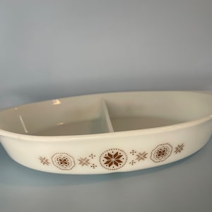May include: White divided casserole dish with a brown geometric pattern. The dish has two sections and is oval shaped.