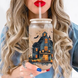 Peut inclure: Un gobelet en verre transparent avec un motif d'Halloween effrayant repr&eacute;sentant une maison hant&eacute;e, des chauves-souris et des citrouilles. Le gobelet est rempli d'un liquide brun et est muni d'une paille.