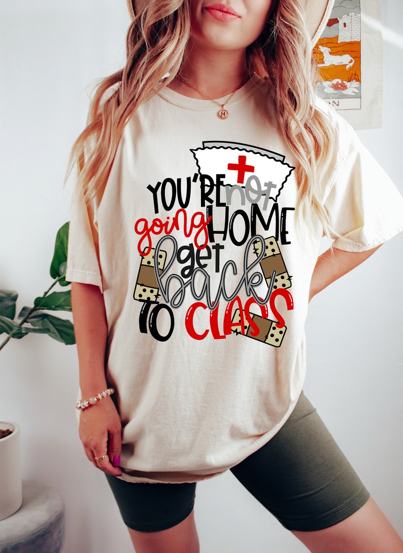 May include: A white t-shirt with a red and black graphic that says "You're not going home get back to class". The graphic includes a nurse's cap with a red cross and band-aid designs.