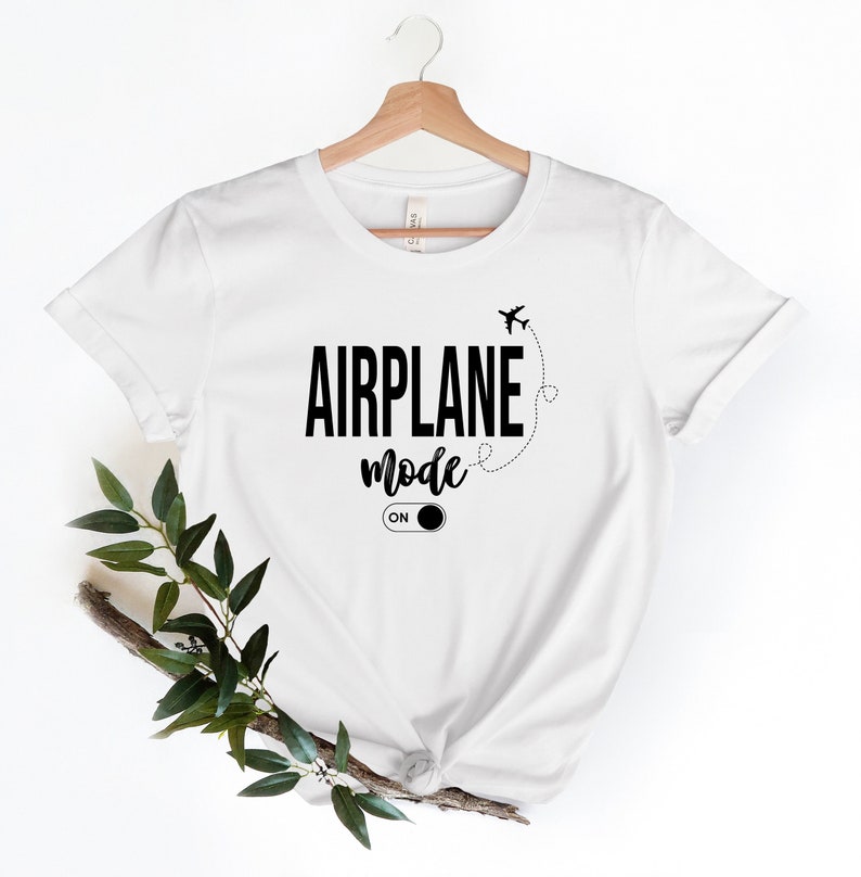May include: White t-shirt with black text that reads "Airplane Mode On" with a stylised airplane and an on/off switch graphic.