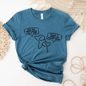 May include: A teal blue t-shirt with a black graphic of two dogs and text that reads "does the name Pavlov ring a bell? no but it makes my mouth water."