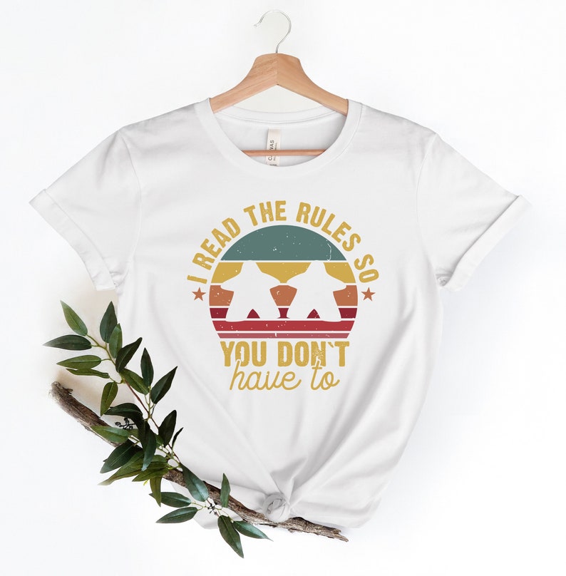 May include: White t-shirt with a vintage-style graphic that says "I read the rules so you don't have to". The graphic features a sunset with two figures in silhouette.