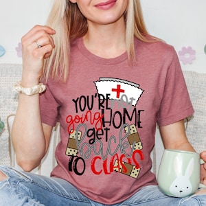 May include: A pink t-shirt with a nurse's hat and the text "You're not going home get back to class" with bandage designs around the text.
