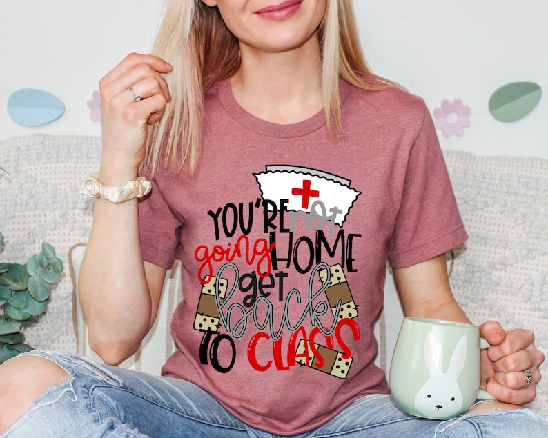 May include: A pink t-shirt with a nurse's hat and the text "You're not going home get back to class" with bandage designs around the text.