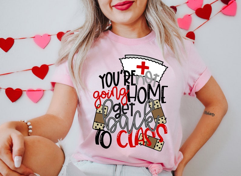 May include: Pink t-shirt with a nurse's cap and the text "You're not going home get back to class" with band-aid graphics.