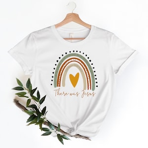 May include: White t-shirt with a rainbow design featuring the text "In the morning, in the sunshine, in the evening, in the healing of the day, every minute, every moment, there was Jesus".