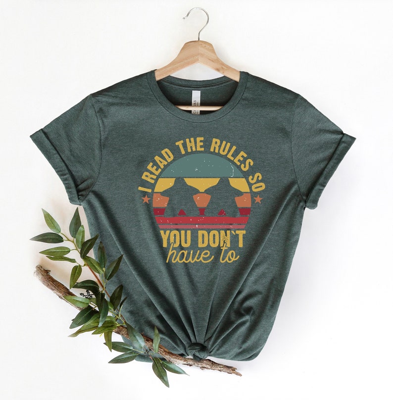 May include: A dark green t-shirt with a vintage-style graphic that says "I read the rules so you don't have to". The graphic features a sunset with three figures in silhouette.
