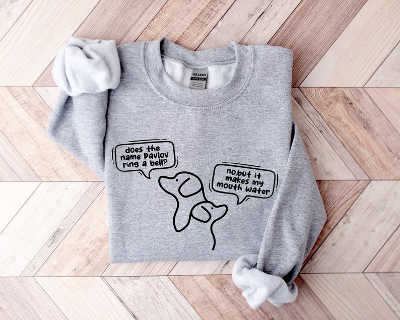 May include: Gray sweatshirt with a black and white illustration of two dogs. The text on the sweatshirt reads "does the name Pavlov ring a bell?" and "no.but it makes my mouth water".