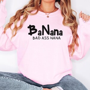 May include: Pink sweatshirt with black text that reads "BaNana Bad Ass Nana".