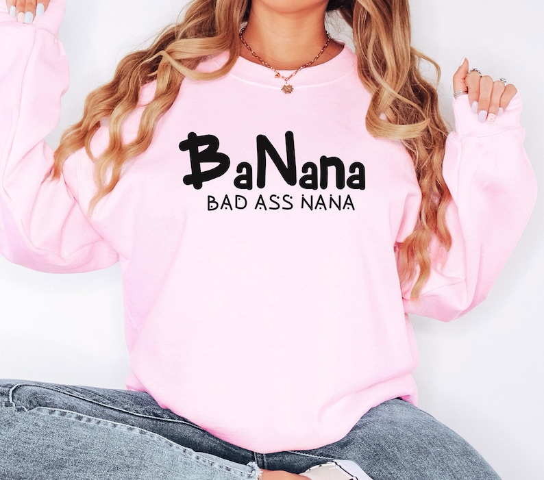 May include: Pink sweatshirt with black text that reads "BaNana Bad Ass Nana".