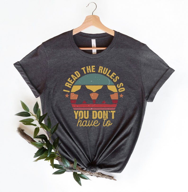 May include: Dark gray t-shirt with a vintage-style graphic that says "I read the rules so you don't have to".