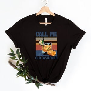 May include: Black t-shirt with a vintage-style graphic of an old fashioned cocktail and the text "Call Me Old Fashioned".