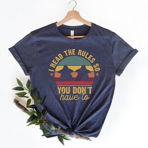 May include: A navy blue t-shirt with a vintage-style graphic that says "I read the rules so you don't have to".