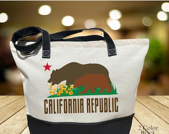 May include: Canvas tote bag with a zip closure. The bag is mainly white with a black base and handles. It displays a graphic of two bears, a red star, and the words "CALIFORNIA REPUBLIC". The bag is designed with a 2-colour black tote bag.