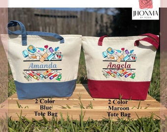 Könnte beinhalten: Zwei personalisierte Tragetaschen mit medizinischem Thema. Die Tasche links ist blau und weiß mit dem Namen "Amanda" bestickt. Die Tasche rechts ist rot und weiß mit dem Namen "Angela" bestickt. Beide Taschen zeigen ein Design aus medizinischen Verbrauchsmaterialien und Geräten.