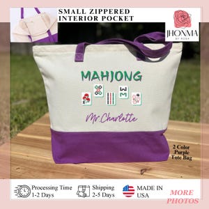 May include: A white canvas tote bag with a purple bottom. The bag has a small zippered pocket on the inside. The bag is personalized with the text "Mahjong" and "Mr. Charlotte" in black. The bag is decorated with four mahjong tiles with red, green, and white designs. The bag is a two-color purple tote bag.