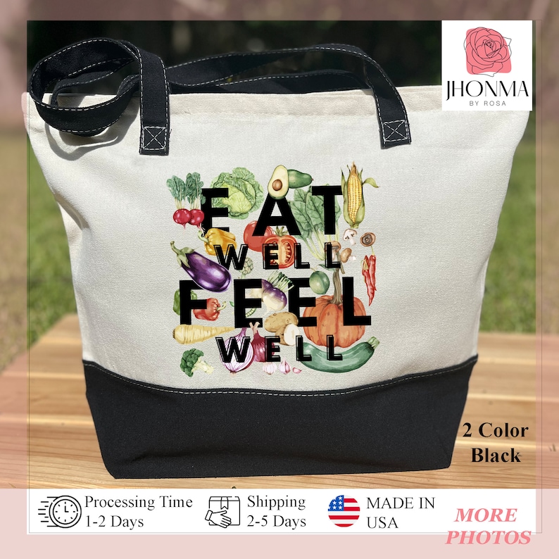 Może przedstawiać: Biała torba z pł&oacute;tna z czarnymi uchwytami i czarnym dnem. Torba ma kolorową ilustrację warzyw i napis "Eat Well Feel Well".
