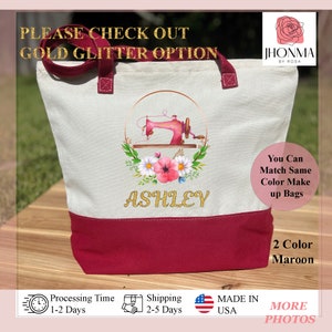 May include: A white canvas tote bag with a maroon bottom. The bag features a gold glitter design of a sewing machine with flowers and the name "ASHLEY". The text "PLEASE CHECK OUT GOLD GLITTER OPTION" is at the top of the image. The text "You Can Match Same Color Make up Bags" is on the right side of the bag. The text "2 Color Maroon" is below the bag. The text "JHONMA BY ROSA" is in the top right corner of the image.