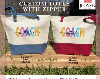 May include: Two canvas tote bags with zipper closures. The bags are personalized with the text "COACH nathalie" in colorful letters. One bag has a blue bottom and the other has a maroon bottom.