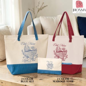 two tote bags, one blue and one maroon, placed on a wooden surface. The bags are labeled with the text "Club Name Book Club" and "Est. 2020".