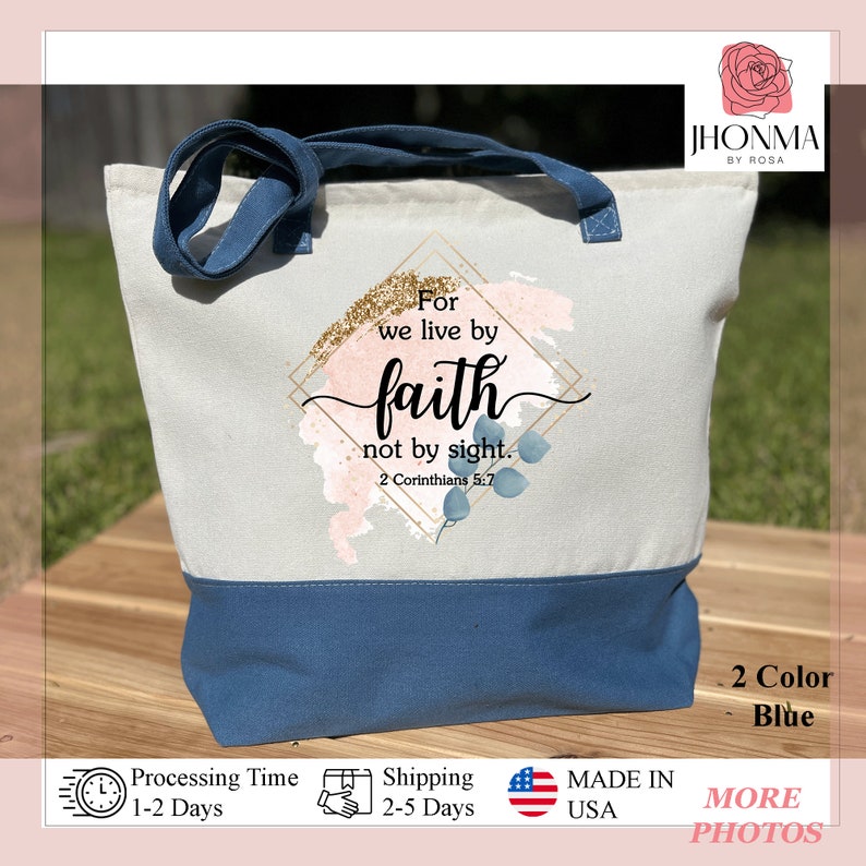 以下が含まれることがあります： 「For we live by faith not by sight. 2 Corinthians 5:7」という文字が印刷された青と白のトートバッグ。バッグは水彩画のデザインで、金色のグリッターのアクセントが施されています。
