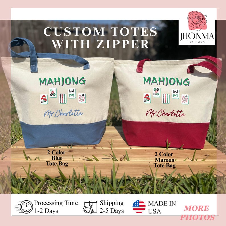 May include: Two custom tote bags with zipper closures. Both bags are white with a blue or maroon bottom. The bags are embroidered with the word "Mahjong" and a design of mahjong tiles. The text "Mr. Charlotte" is also embroidered on each bag.