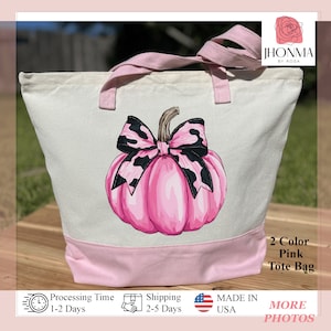 May include: A pink tote bag with a pink pumpkin and a black and white bow. The bag has a pink bottom and white top. The text "2 Color Pink Tote Bag" is on the bag.