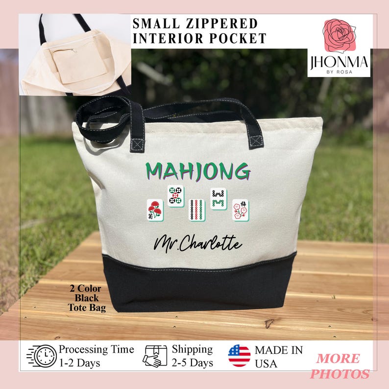 May include: A white canvas tote bag with black handles and a black bottom. The bag has a small zippered interior pocket. The bag is personalized with the text "MAHJONG" and "Mr. Charlotte" in black lettering. The bag also features a graphic of mahjong tiles.