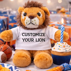 Puede incluir: Un león de peluche con una camiseta blanca con el texto "CUSTOMIZE YOUR LION". El león tiene una melena marrón y pelaje naranja. Una magdalena con una vela a rayas azules y blancas encendida está al lado del león. Balones de baloncesto y regalos envueltos en el fondo.