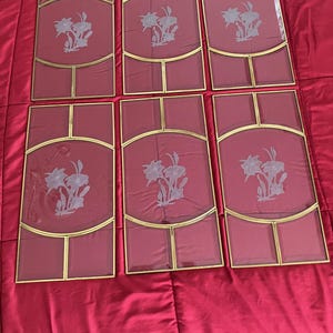 May include: Six glass panels with gold trim and etched floral designs. Each panel has a different design, but all feature a similar floral motif.