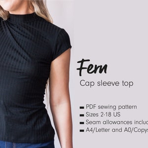 Può includere: Top nero a maniche corte con collo alto e texture a coste. L'immagine include il testo "Fern" e "Cap sleeve top". Il modello è disponibile nelle taglie 2-18 US.