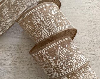 May include: A roll of burlap ribbon with a repeating pattern of white gingerbread houses. The ribbon is tan with a textured appearance. The houses have detailed windows, doors, and decorative elements. The ribbon is rolled up, showing the pattern.