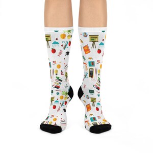 May include: White socks with a colorful pattern of school supplies, including books, pencils, a microscope, a graduation cap, and a rain cloud.