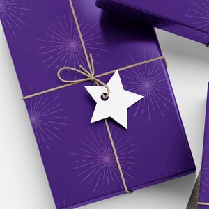 May include: A wrapped gift with purple paper featuring a burst pattern. The package is tied with twine and a white star-shaped tag. The overall theme is gift-giving and celebration.