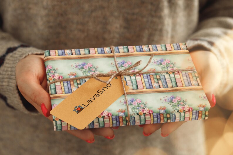 May include: A gift wrapped in paper with a bookshelf and floral design. The paper is light blue with brown shelves and colorful books. The gift is tied with twine and a brown tag that says "LavaSno".