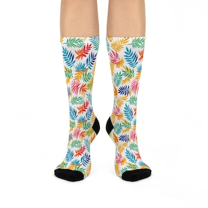 May include: A pair of white socks with a colorful tropical leaf pattern. The socks are black at the toes and heels.